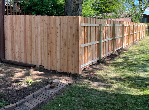 Long, natural colored fence around house.
